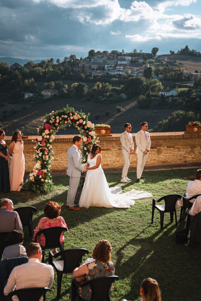 Hochzeitspaar unter einem Blumenbogen mit Blick in die Landschaft